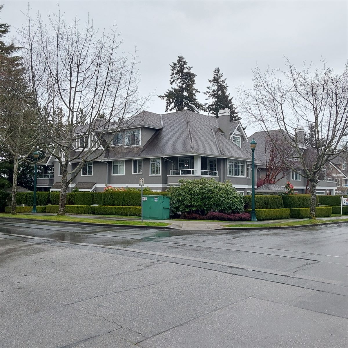 Grey low-rise residential building on a corner lot, Delta